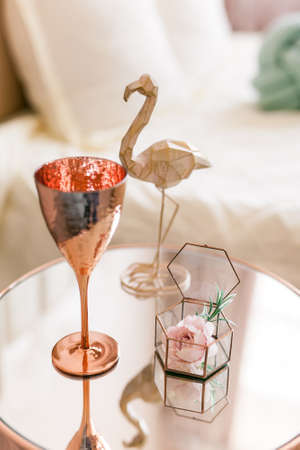 Coffee table, metal, mirror. Close-up of decor, flamingo statuette, fashionable glass, glass casket with a flower in clean modern interiorの写真素材