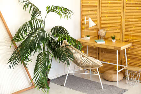 Cozy Workplace with table, rattan chair, white lamp in living roomの写真素材