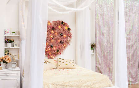 Cozy white wooden romantic bedroom in a four-poster apartment with a large fluffy heart on the wall