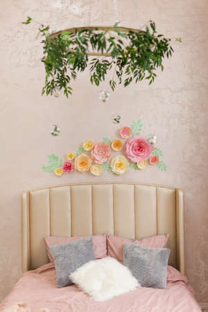 Beautiful loft bedroom in pink pastel colors, with home plants, paper flowers decoration on the wall and a wooden circle above the bedの写真素材