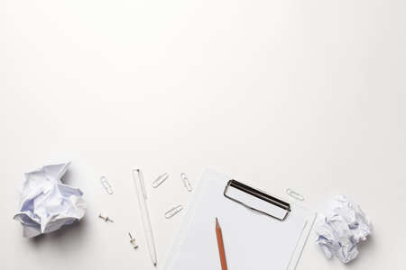 White office table desk. Work pace with clip board, pen, crumpled paper balls, top view on white background with Copy space.の写真素材