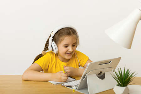 Caucasian girl student wear headphone study online with video call teacher, Happy young girl learning. student using laptop talking in webcam video chat learning lesson with distance teacher.の写真素材