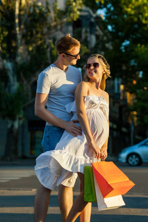 Portrait of happy people with husband and pregnant wife shopping and having fun in city street
