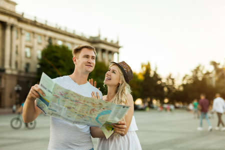 summer holidays, dating and tourism concept - smiling couple in sunglasses with map in the cityの写真素材