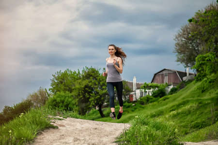 Jogging woman running in park in sunshine on beautiful summer day. Sport fitness model of Caucasian ethnicity training outdoor for marathon.の写真素材