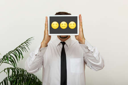 Customer service concept, businessman holding digital tablet with emoticons and rating for his satisfactionの写真素材