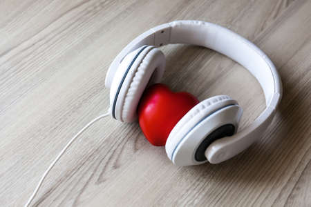 White headphones with red heart sign in the middle on wooden table. Love music conceptの写真素材