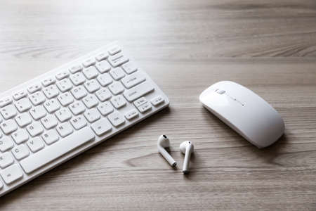 keyboard, mouse and wireless headphones on top of wooden desk.の写真素材