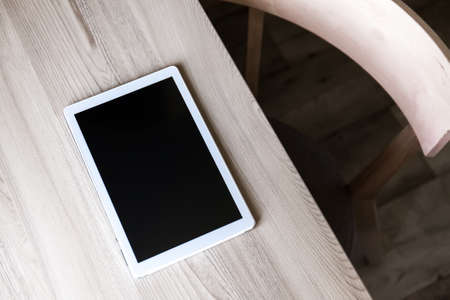 Office table with white tablet pc, computer and wooden chair. top view of the workplace
