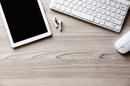 The office desk flat lay view with keyboard, mouse, tablet pc and wireless earphone on wood texture background.の写真素材