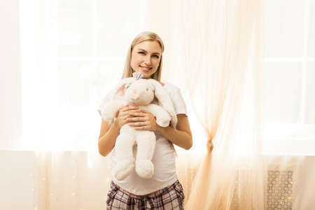 Portrait of pregnant woman with toy bunny. Pregnancy, parenting, preparation and expectation concept.の写真素材