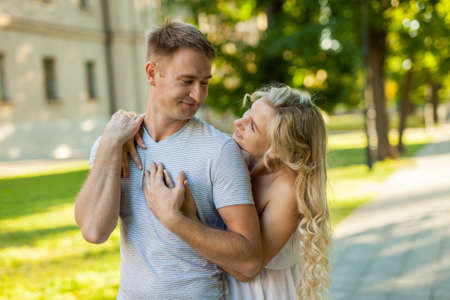Happy to be together. Portrait of beautiful young loving couple smiling look at each other while standing outdoorsの写真素材