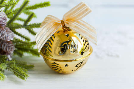Golden jingle bell Christmas bauble with text Joy gold ribbon snowy abstract background and...