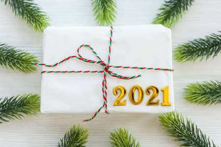 Christmas present and Happy New Year 2021 on wooden background. Handmade gift Christmas box, fir branches, craft paper, top view.の写真素材