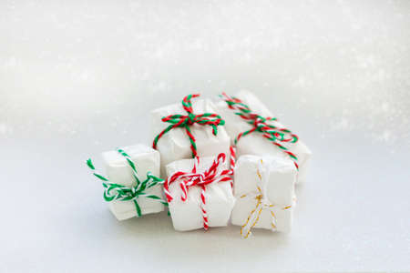 collection of Christmas gifts with candy striped ropes on a white sparkling snow backgroundの写真素材
