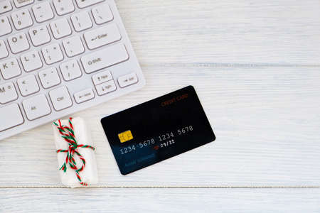 Concept online shopping buying presents. Credit card, keyboard and christmas present on white table flat lay, copy space. Business christmas holidays concept, holiday gift online shopping concept.の写真素材