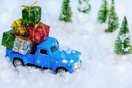 Vintage blue truck carrying many gifts through the snowy forest. Christmas and holiday concept