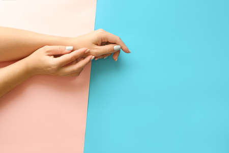 Stylish trendy geometric with stripes female manicure. Beautiful young woman's hands on pink and blue background.の写真素材
