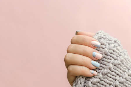 Female hand manicure close up view with knitted sweater on pink background. Trendy Geometric Nail Art Manicure. Manicure salon banner conceptの写真素材