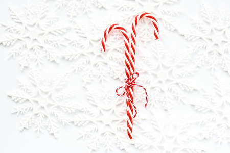 Christmas Candy canes with striped rope bow on white background with snowflakes. Sweet christmas...