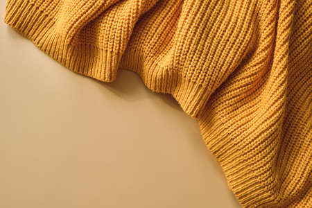 Yellow orange women's autumn knitted sweater on pastel beige background. Creative clothing concept, trendy fall winter cozy sweater pullover. Women's fashion, autumn discounts. Shoppingの写真素材