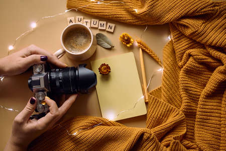 Autumn still life woman in a warm knitted cozy sweater holding a Camera. autumn mood flat layの写真素材
