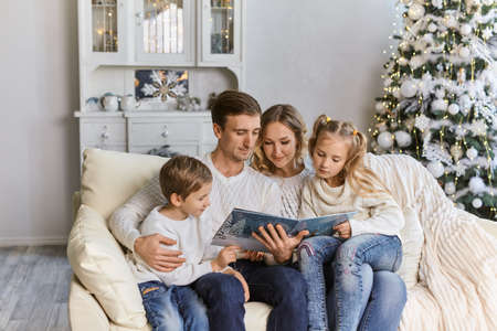 Portrait of friendly family reading book on Christmas eveningの写真素材