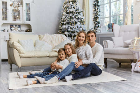 Shot of happy young family sitting on the floor with their two children and enjoy relaxing at home.の写真素材