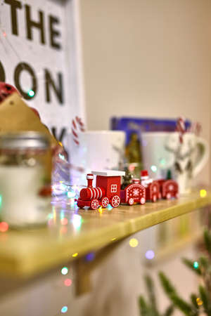 Christmas decor in the interior of the house: a wooden shelf on which stands a toys, cups and train