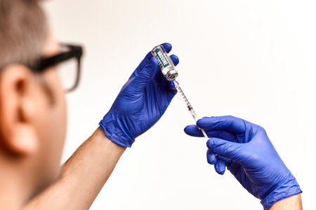 Doctor, nurse, scientist, wearing glasses hand in blue gloves holding vaccine disease preparing for vaccination, medicine and drug concept.の写真素材