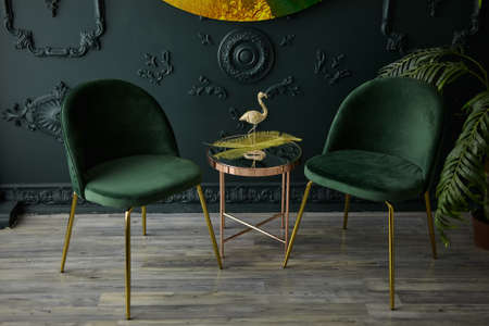 Cozy modern seating space with golden stainless mirror table and velvet chairs in natural light...