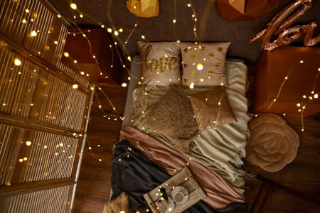 Romantic interior in brown colors with bed, pillows, blankets and Garland. Wooden tray with cups. 3d hearts on the wall. Selective focusの写真素材