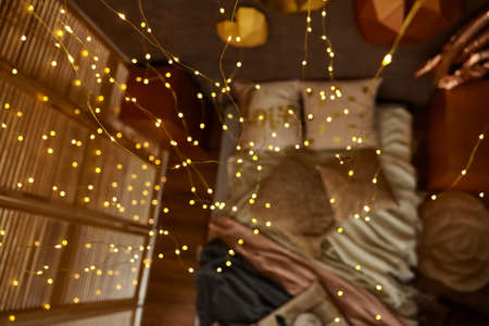 Romantic interior in brown colors with bed, pillows, blankets and Garland. Wooden tray with cups. 3d hearts on the wall. Selective focus, out of focus, bokehの写真素材