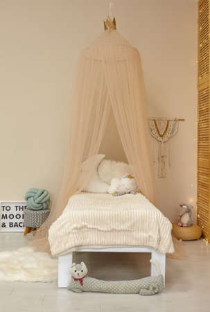 Cute child's room interior with toys and modern furniture, bed with tentの写真素材