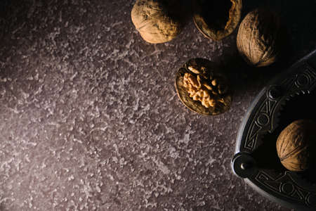 Vintage walnut cracker and walnuts on a dark texture background. Top view, flat lay. Copy space.
