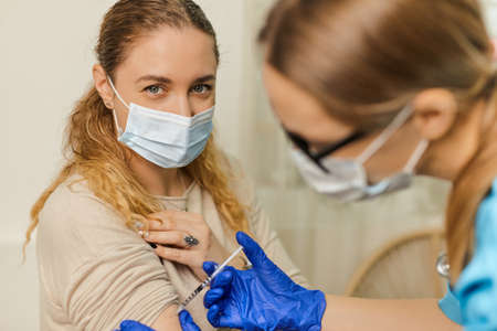 Young woman doctor vaccinates a young woman in the office of a medical clinic