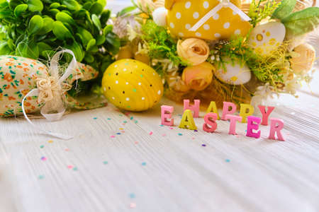 Colorful easter basket a white wooden background, decorated with blossom spring. Springtime holidays congratulatory concept with wooden text Happy Easter. Copy spaceの写真素材