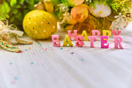 Colorful easter basket a white wooden background, decorated with blossom spring. Springtime holidays congratulatory concept with wooden text Happy Easter. Copy spaceの写真素材