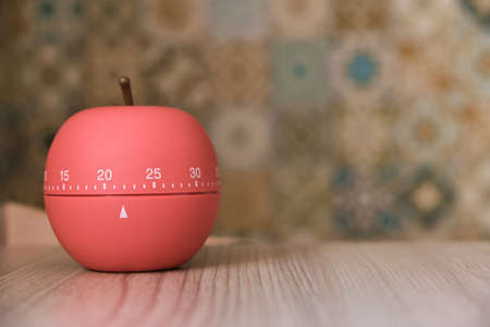 Kitchen timer shaped like a apple on a sunny kitchen on the table, counting down twenty two minutesの写真素材