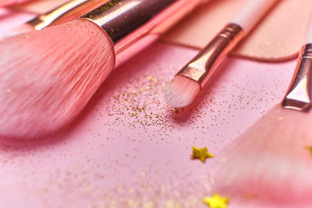 Close up Makeup brushes and shiny sparkles on pink background. Festive magic make up concept. Top view Flat Lay, Macro, Selective focusの写真素材