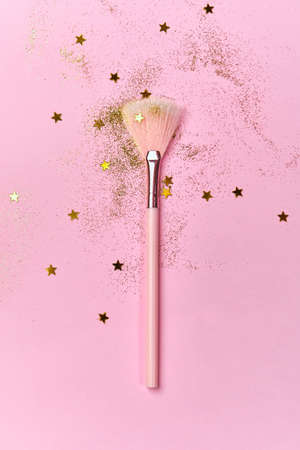 Makeup brush, scattering golden sparkles and shining stars on pink background. Festive magic make up concept. Top view Flat Lay, Macro, Selective focusの写真素材