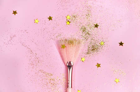 Makeup brush, scattering golden sparkles and shining stars on pink background. Festive magic make up concept. Top view Flat Lay, Macro, Selective focusの写真素材