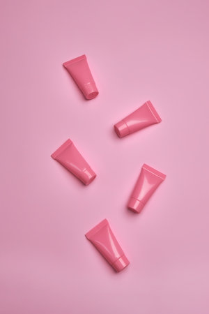 Blank pink cosmetic tubes on pink background. Packaging cream containers design. Flat lay, top view.の写真素材