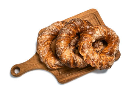 Delicious sweet sugar ring buns on a wooden cutting board. Isolated on white background. Homemade bakingの写真素材