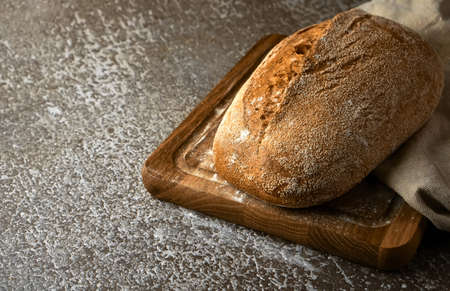 Wholegrain rye bread on a cutting board on gray background. Selective focus, Copy space for text