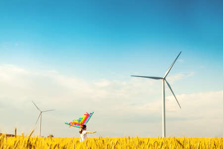 Happy Little girl running in a wheat field with a kite in the summer. Well-planned and active weekend. Happy childhood.の写真素材