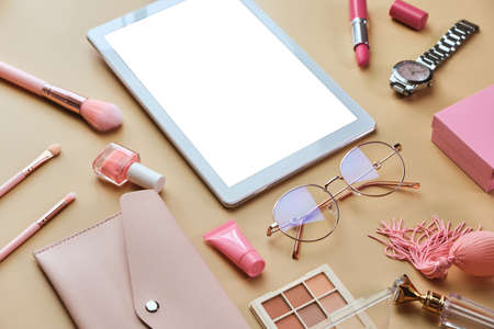 Flat lay, top view modern office table desk. Workspace with white tablet, notepad, glasses, pens, beauty accessories on pastel beige background. Online work, shopping, courses and training conceptの写真素材