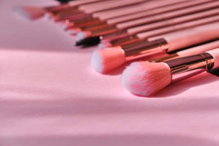 Gorgeous set of professional fluffy pink makeup brushes on a pink background. Close-up. Selective...