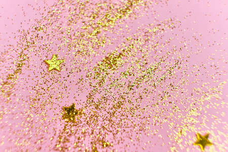 Golden glitter sequins and stars on a pink background. Universal festive background. Horizontal,...