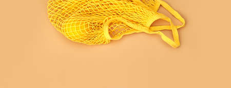 Mesh shopping bag with lemon on beige canvas background. Banner for designの写真素材